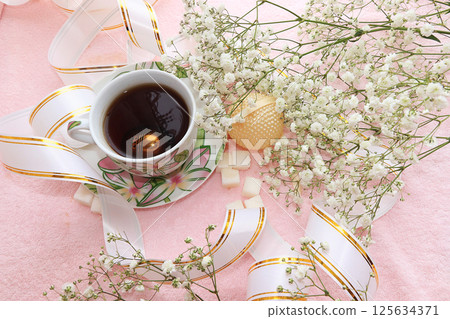 cup of coffee and flowers in festive packaging, good morning on a pink background in a cozy home 125634371