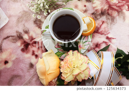 A cup of coffee and a rose on a pink background, a lemon and a festive ribbon on the morning table, good morning wishes 125634373