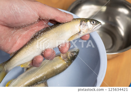 Removing the slippery surface of ayu fish with salt (stock photo) 125634421