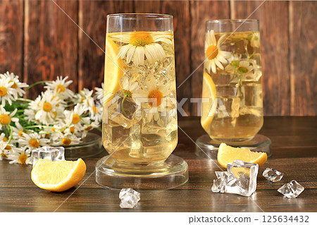 Chamomile tea with lemon in transparent glasses with natural small chamomile flowers on a rustic table, concept of medicinal herbal tea and proper natural nutrition, summer card, Chamomile tea with lemon in transparent glasses with natural small chamomile flowers on a rustic table, concept of medicinal herbal tea and proper natural nutrition, summer card, 125634432
