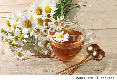 Chamomile tea with lemon in transparent glasses with natural small chamomile flowers on a rustic table, concept of medicinal herbal tea and proper natural nutrition, summer card, 125634433