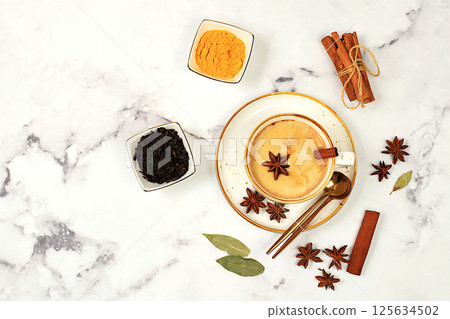 Indian masala chai tea with milk, ginger, anise and cinnamon on an old concrete table. Traditional drink with spices and herbs, cafe concept, restaurant advertising and menu. Selective focus 125634502