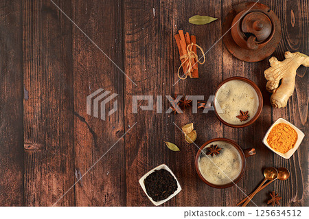 Indian masala chai tea with milk, ginger, anise and cinnamon on an old wooden table. Traditional drink with spices, cafe concept, advertising for restaurant and menu. Selective focus 125634512