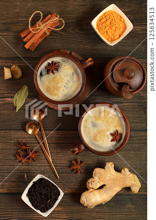 Traditional drink with spices,Indian masala chai tea with milk, ginger, anise and cinnamon on an old wooden table. cafe concept, advertising for restaurant and menu. Selective focus 125634513