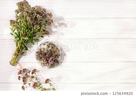 Collection of useful herbs for treatment according to folk recipes. Bouquet of fresh oregano flowers and dried petals in a cup on a wooden table, alternative traditional medicine concept, Collection of useful herbs for treatment according to folk recipes. Bouquet of fresh oregano flowers and dried petals in a cup on a wooden table, alternative traditional medicine concept, 125634920