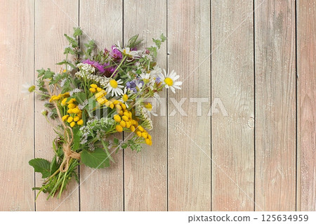 Floral arrangement of wild herbs and flowers on a wooden table, rustic style, autumn background, Bouquet of tansy, mint, celandine, chamomile and yarrow, collection of useful herbs for treatment 125634959