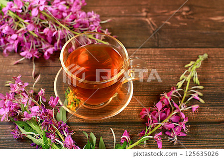 Medicinal herbal tea or fireweed infusion in a glass cup with flowers, the concept of alternative traditional medicine, green pharmacy advertising, collection of useful herbs for treatment according 125635026
