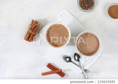 Coffee drink with milk and whipped cream, cappuccino coffee, latte, cinnamon, coffee beans on a gray concrete table, modern coffee shop advertisement, selective focus, top view, space for text, 125635085