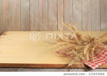 Empty wooden table with sheaf of wheat on old background with place for text, rustic style, bakery and harvest concept, mock up for design and showcase for product showcase, selective focus 125635668