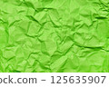 A textured green crumpled paper background with natural creases and folds. Ideal for design projects, digital graphics, or creative presentations requiring a vibrant, tactile surface element 125635907