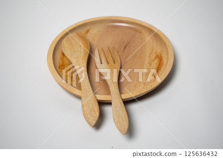 Minimalist wooden tableware set showcasing a spoon, plate, and fork in a flat lay composition. 125636432