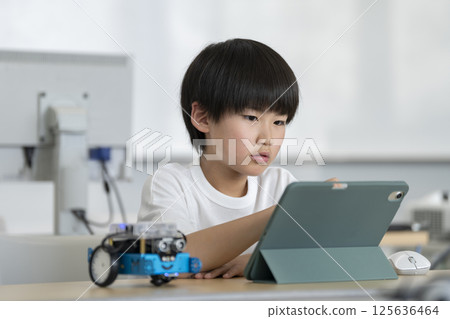 A fourth grade boy programming a robot 125636464