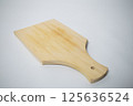 A plain wooden cutting board with a smooth surface and light wood grain, perfect for kitchen use. 125636524