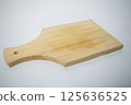 A plain wooden cutting board with a smooth surface and light wood grain, perfect for kitchen use. 125636525