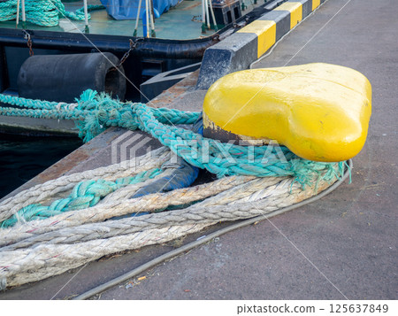 Mooring tied to the bollard. Maritime business. The concept of the ship on the pier. Ship parking. 125637849