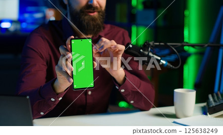 Content creator reviewing mockup phone received from sponsor, doing influencer marketing. Media star advertising isolated screen smartphone during sponsorship promotion, camera A close up Content creator reviewing mockup phone received from sponsor, doing influencer marketing. Media star advertising isolated screen smartphone during sponsorship promotion, camera A close up 125638249