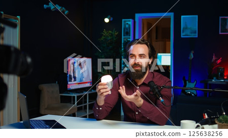 Smart light bulb used by tech specialist in studio to teach audience how to fix it, handheld camera shot. Focus on IoT home automation product held by media star, camera B Smart light bulb used by tech specialist in studio to teach audience how to fix it, handheld camera shot. Focus on IoT home automation product held by media star, camera B 125638256