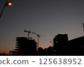 Silhouettes of tower cranes at the construction site of high-rise buildings at sunset 125638952