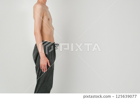 A thin Japanese man standing calmly, looking to the side and standing upright 125639077