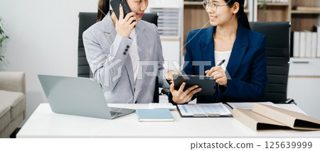 Businesswomen work and discuss their business plans. A women employee explains and shows her colleague in office. 125639999