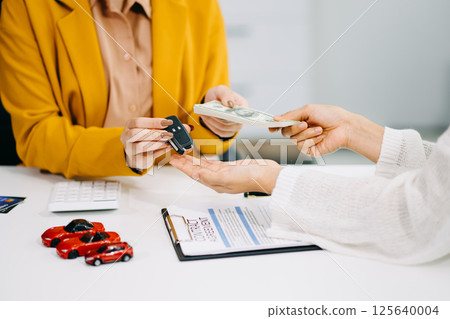 Asian people car salesman or sales manager offers to sell a car and explains of signing a car contract and signing car insurance document Asian people car salesman or sales manager offers to sell a car and explains of signing a car contract and signing car insurance document 125640004