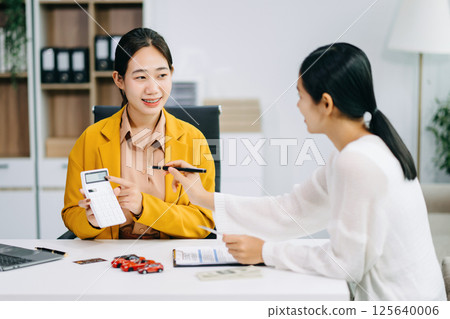 Asian people car salesman or sales manager offers to sell a car and explains of signing a car contract and signing car insurance document Asian people car salesman or sales manager offers to sell a car and explains of signing a car contract and signing car insurance document 125640006