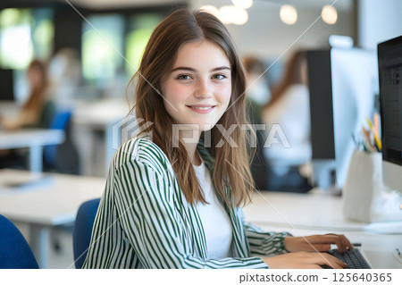 外國女人微笑。一位年輕女子在明亮的教室裡使用電腦工作的肖像 125640365