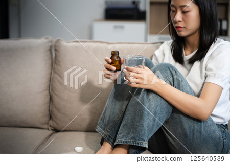 woman sit Depression Dark haired  pensive glance Standing by window on sofa and anxiety 125640589