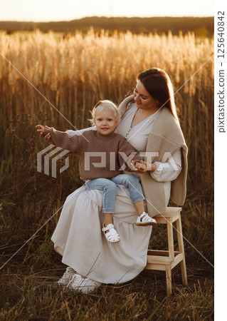 Mother and Daughter Smiling in Wheat Field at Sunset 125640842