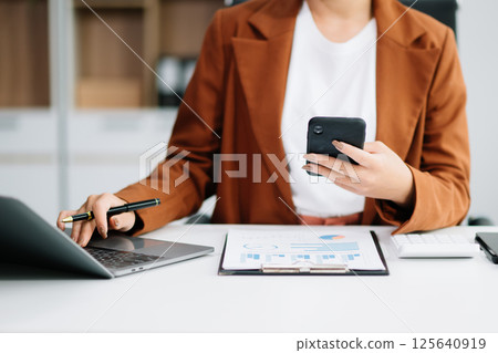 Beautiful Asian business woman typing laptop and tablet Placed at the table Beautiful Asian business woman typing laptop and tablet Placed at the table 125640919