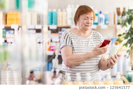 Checking expiration date of shampoo or shower gel - female shopper scans QR code on label of shampoo using smartphone 125641577