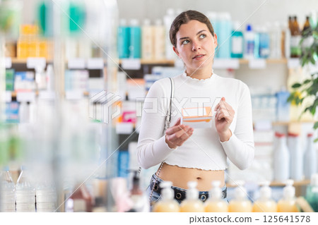woman in summer clothes chooses a package of pallets in a pharmacy woman in summer clothes chooses a package of pallets in a pharmacy 125641578