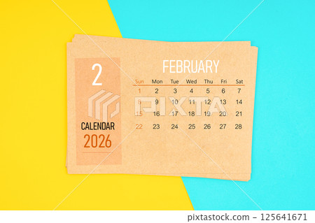Brown calendar card for February 2026 year on yellow and blue background. 125641671