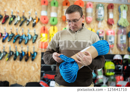 Male tourist chooses and buys climbing rope for an autumn hike in tourist equipment store Male tourist chooses and buys climbing rope for an autumn hike in tourist equipment store 125641710