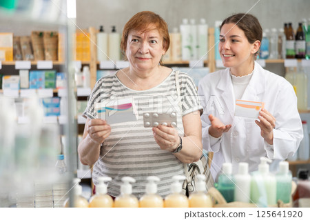 mature woman chooses paracetamol and consults a pharmacist mature woman chooses paracetamol and consults a pharmacist 125641920