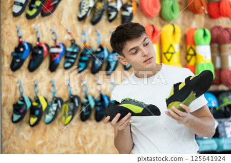 Guy chooses light summer sports shoes for hiking in sports store 125641924