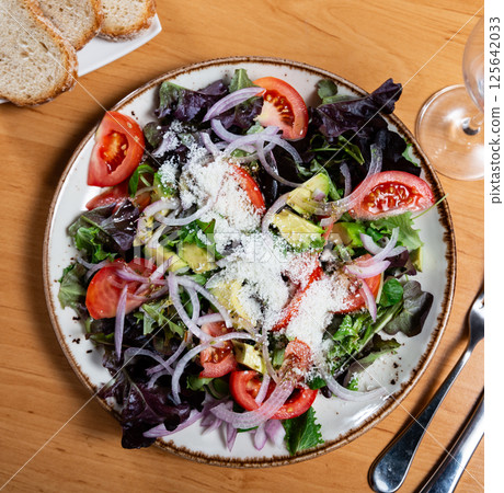 Fresh salad made of avocado, tomato, cheese and onion rings 125642033
