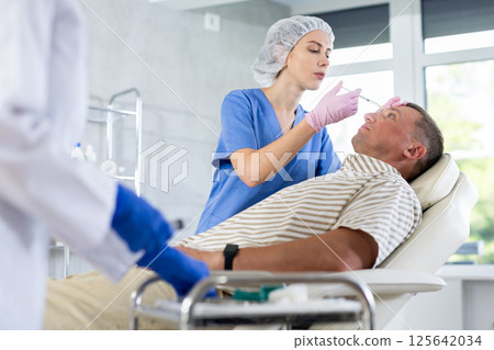 Man applying rejuvenating treatments by female doctor. 125642034