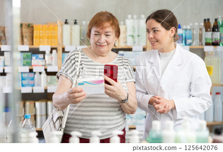 Woman buyer scans pills qr code with woman pharmacist 125642076