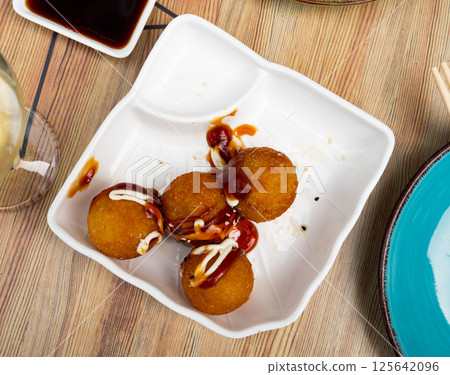 Toasted takoyaki balls containing octopus, seasoned with ketchup and mayonnaise. 125642096