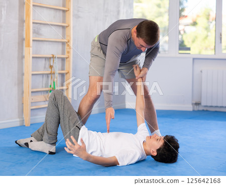 Teenage boy and middle-aged man training throwing method during self-defense courses 125642168