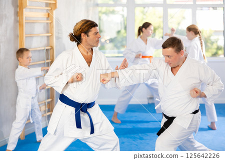 Man father is paired with coach to learn how to strike and rehearses blocking opponent 125642226