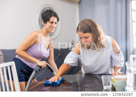 Two young women cleaning living room. Concept of homosexual family relationships Two young women cleaning living room. Concept of homosexual family relationships 125642297