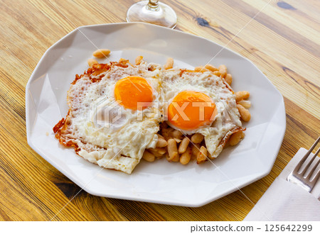 Fried eggs with stewed white beans for breakfast Fried eggs with stewed white beans for breakfast 125642299