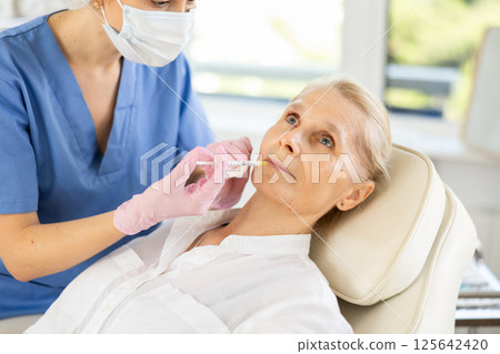 Woman applying rejuvenating treatments by doctor. 125642420