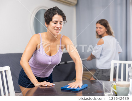 Young female couple cleaning living room together 125642489