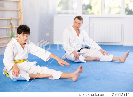 Man and boy teenager doing stretching in studio Man and boy teenager doing stretching in studio 125642515