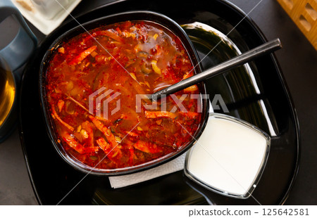 Delicious meat soup solyanka on broth served with sour cream and herbs closeup 125642581