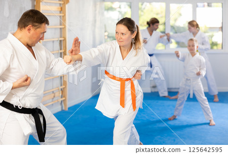 Woman is paired with man teacher to learn how to strike and rehearses blocking opponent 125642595