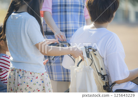 年輕護工:推著輪椅的小學生和護工 年輕護工:推著輪椅的小學生和護工 125643229